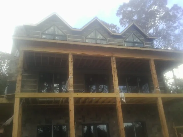 Dormers and porch framing on a large log home under construction — Roof Coating work by our crew in Zimmerman