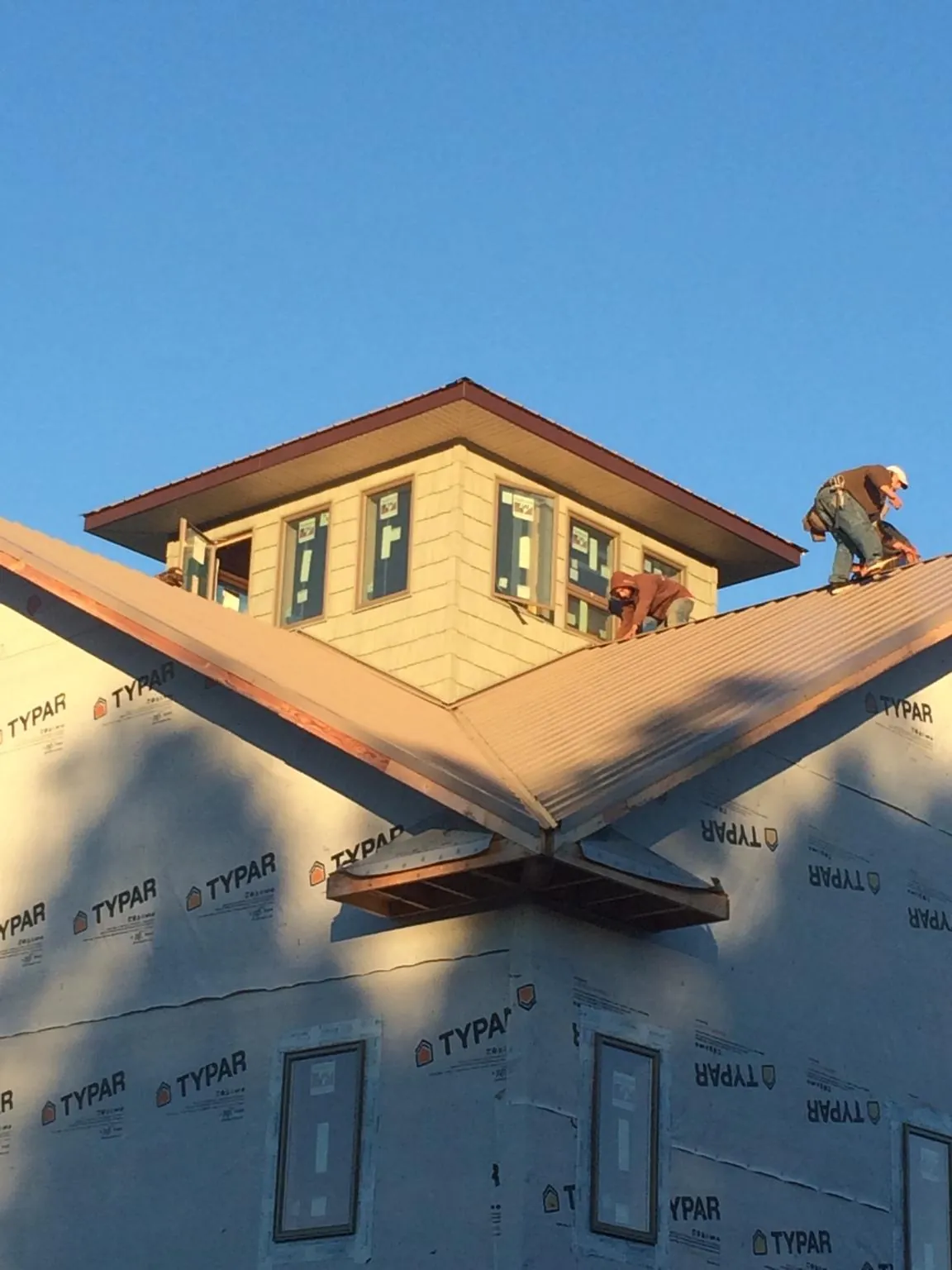 Roofers working around a rooftop cupola on a new metal roof at sunset — Roof Waterproofing in Zimmerman by Roofing Brothers
